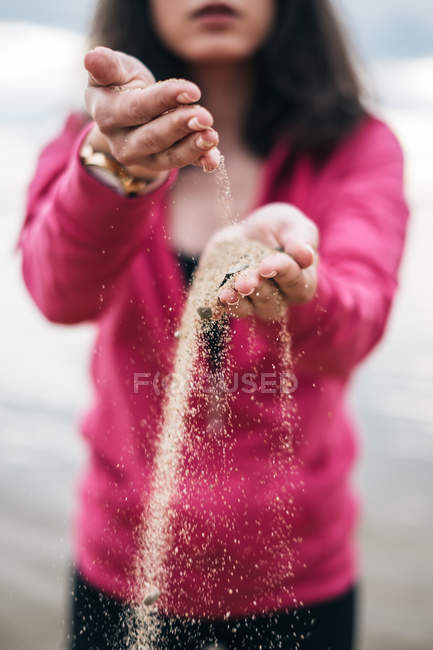 Woman with sand running through hands — Stock Photo