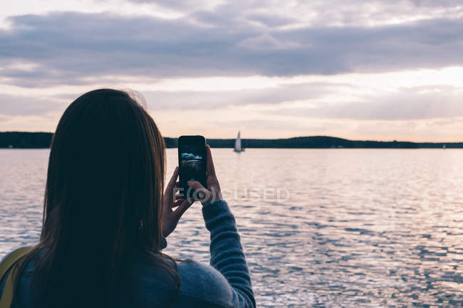 Mulher tirando foto de barco à vela — Fotografia de Stock