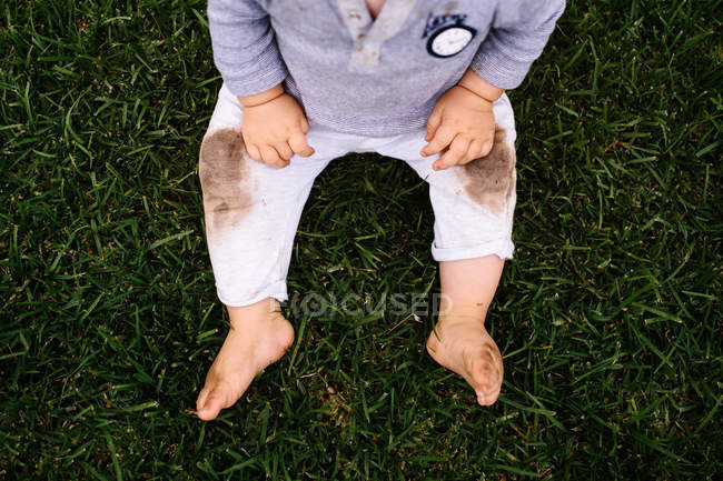 Niño sentado en la hierba - foto de stock