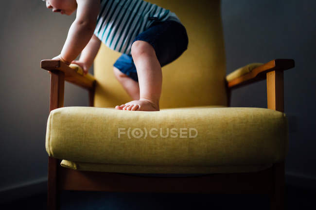 Bébé garçon debout sur chaise — Photo de stock
