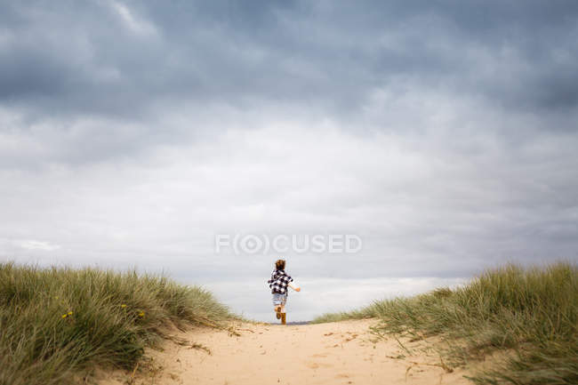 Menina correndo através de dunas de areia — Fotografia de Stock