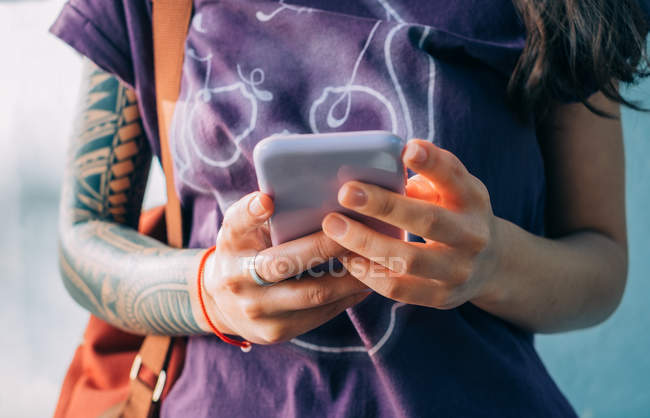 Woman with tattoos texting on mobile phone — Stock Photo