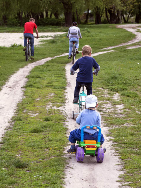 Famille fait du vélo le long de la route de terre — Photo de stock