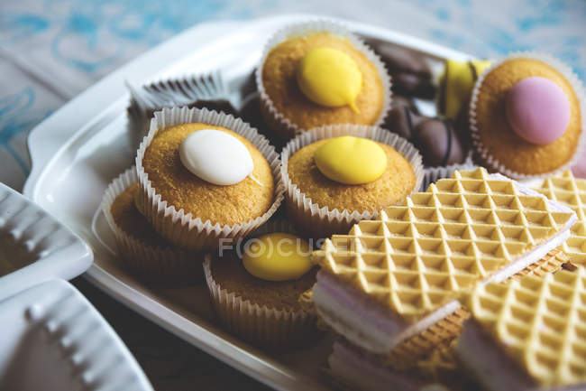 Nahaufnahme von süßen Cupcakes und Waffeln auf einem Tablett — Stockfoto
