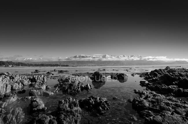 Nueva Zelanda, Kaikoura, imagen monocromática de la playa rocosa y las montañas - foto de stock