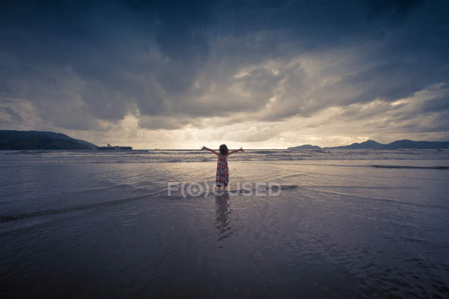Girl standing with arms up in water in nature — Stock Photo