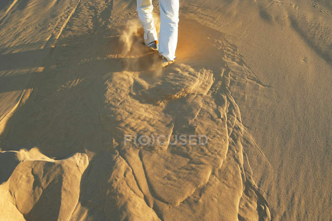 Cropped image of Man running up sand dune — Stock Photo