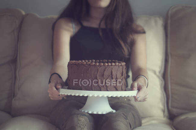 Gros plan de fille tenant gâteau au chocolat sur un stand de gâteau — Photo de stock