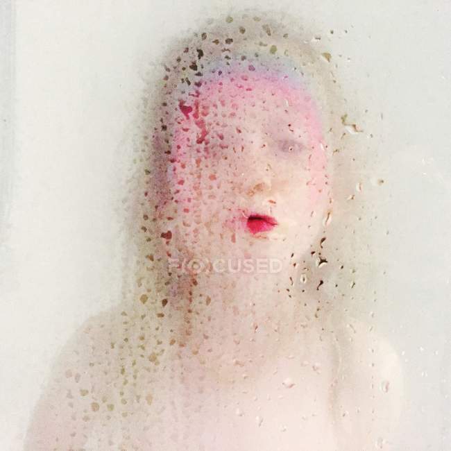 Retrato de niño con cara de arco iris impreso de pie detrás de la puerta de la ducha - foto de stock