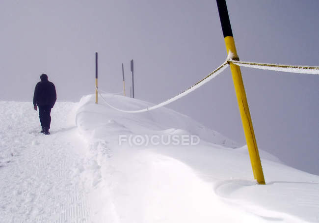 Hombre caminando en la nieve en la pendiente con postes - foto de stock