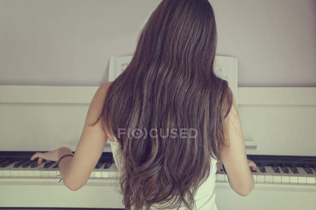 Вид сзади девушки, играющей на пианино — стоковое фото