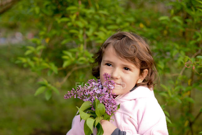 Kleines Mädchen mit einem Strauß fliederfarbener Blumen — Stockfoto