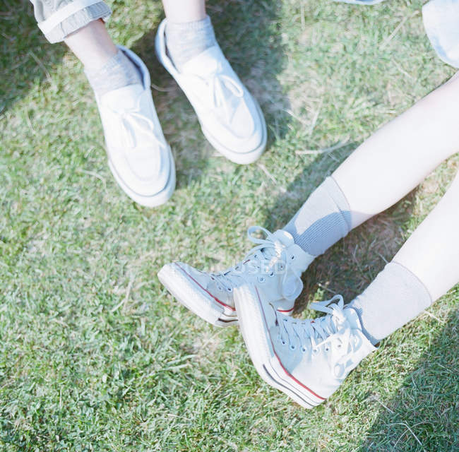 Vista close-up de pés em sapatos brancos na grama verde — Fotografia de Stock