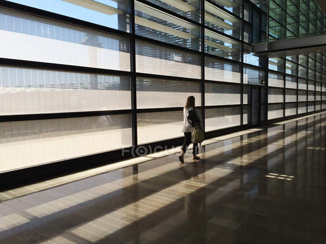 Vista posteriore della donna che cammina attraverso l'aeroporto moderno vuoto — Foto stock