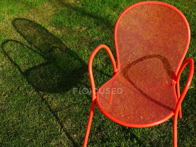 Nahaufnahme eines orangefarbenen Stuhls im grünen Gras — Stockfoto