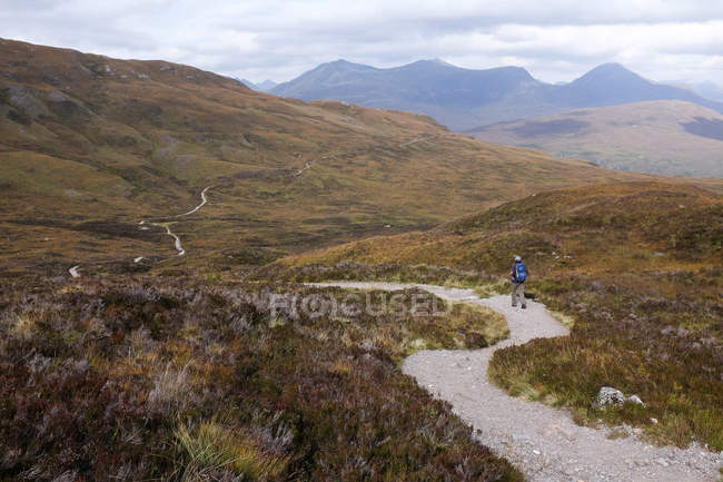 Caminata de hombres en el camino en las montañas, Highlands, Escocia, Reino Unido - foto de stock