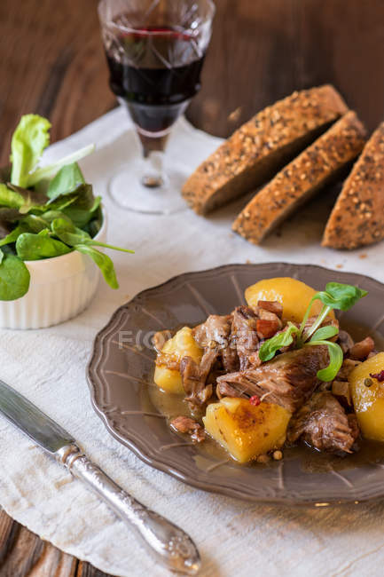 Wein, Brot, grüner Salat und Fleisch über dem Esstisch — Stockfoto