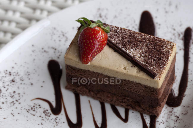 Fatia de bolo de chocolate decorado com morango na placa — Fotografia de Stock