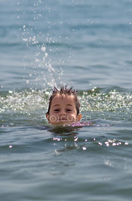 Primer plano de niño feliz nadando en el mar - foto de stock