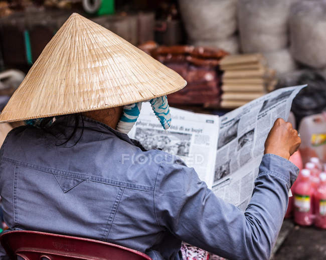 Vista trasera del periódico Woman reading, Vietnam, Ciudad Ho Chi Minh - foto de stock