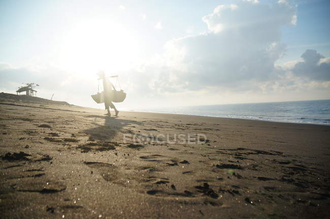 Silhouette eines traditionellen Salzbauern, der im Meer steht, Dorf Kusamba, Bali, Indonesien — Stockfoto