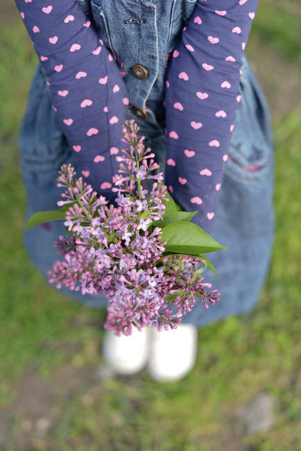 Primer plano de Chica sosteniendo ramo de flores de color lila - foto de stock