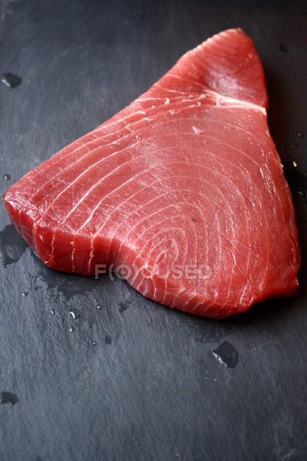 Tasty raw tuna steak on slate, closeup — Stock Photo