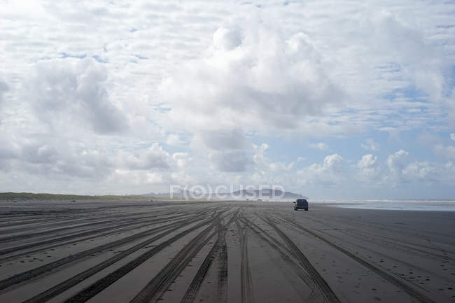Scenic view of car driving on an empty sandy beach — Stock Photo