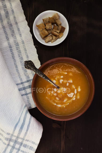 Vue du dessus du bol de soupe à la citrouille et croûtons sur table en bois — Photo de stock