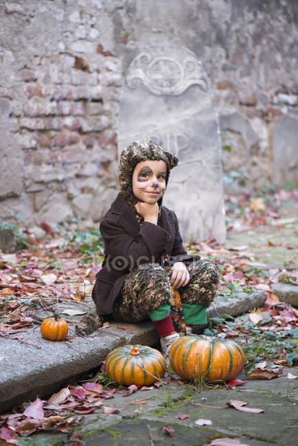 Boy wearing Halloween costume sitting in cemetery — Stock Photo