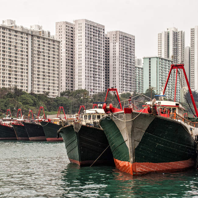 View of anchored boats and modern city buildings on background — Stock Photo