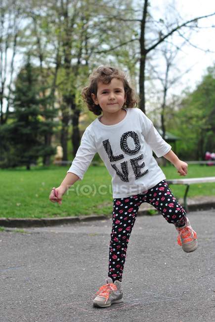Girl playing hopscotch on street and looking at camera — Stock Photo