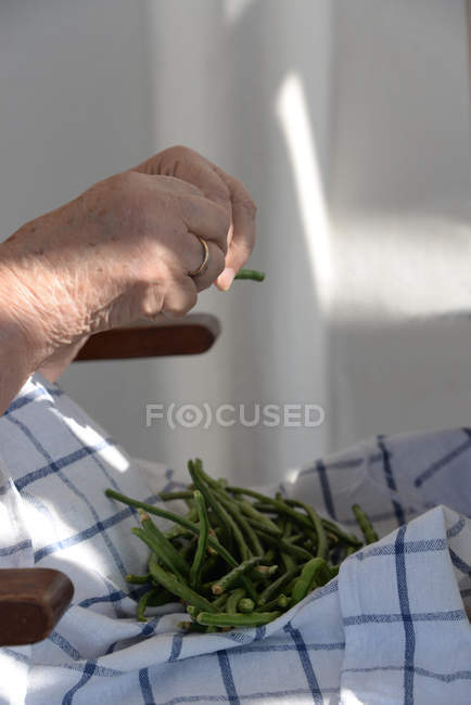 Manos femeninas preparando judías verdes en toalla de cocina - foto de stock