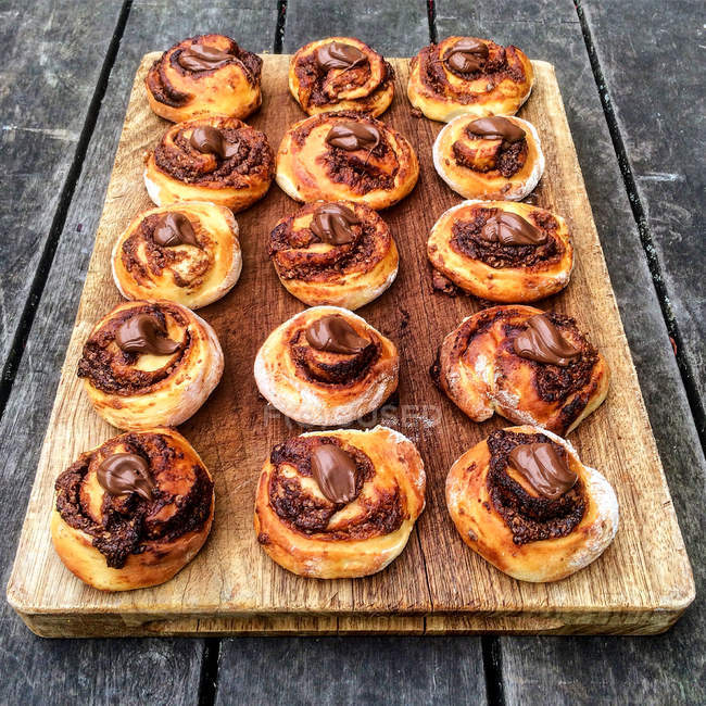 Chocolate swirl buns on wooden chopping board — Stock Photo