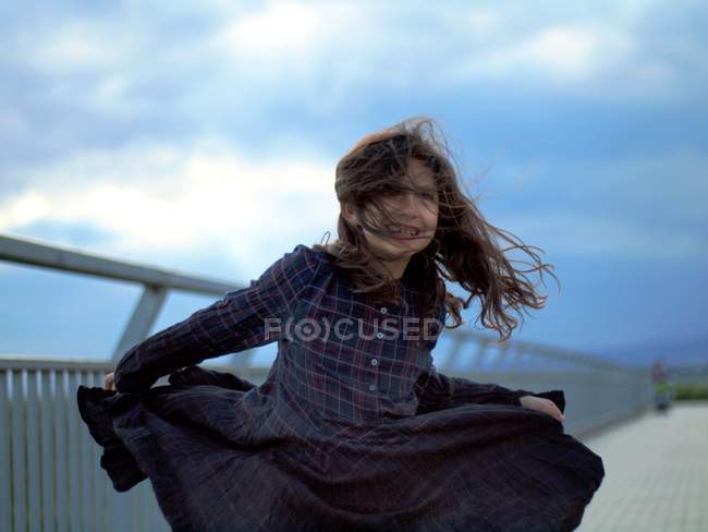 Girl wearing checkered dress dancing in wind — Stock Photo