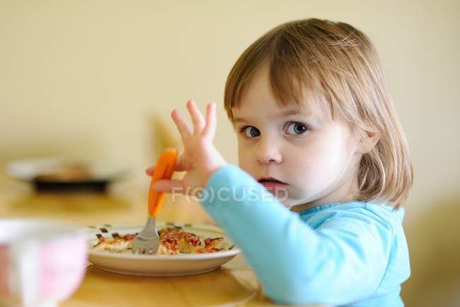 Linda menina sentada à mesa e jantando — Fotografia de Stock