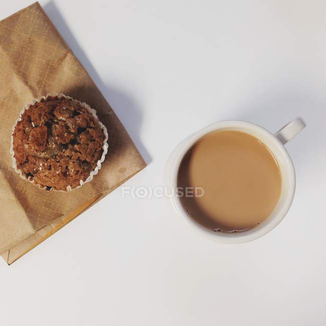 Draufsicht auf klassisches süßes Frühstück, Schokoladenmuffin und Kaffeetasse über weißem Tisch — Stockfoto
