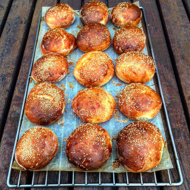 Tasty fresh baked bread rolls on wire rack — Stock Photo