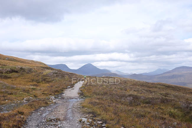 Задній вид людина Маунтінбайкінг на шляху, нагір'я, Шотландія — стокове фото