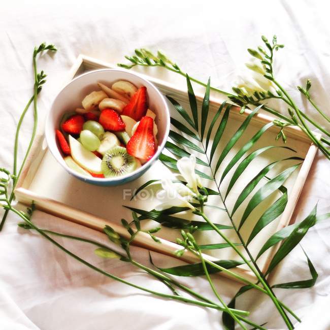 Insalata di frutta fresca su un vassoio con decorazioni floreali — Foto stock