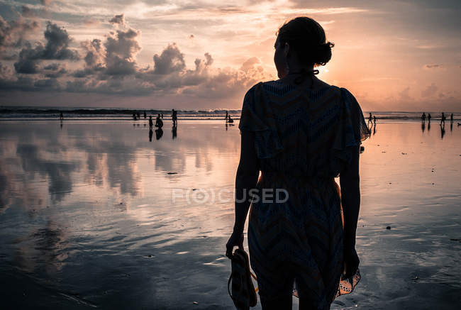 Индонезия, Бали, Легиан, Силуэт женщины, стоящей на пляже на закате — стоковое фото