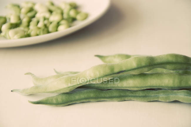 Lima beans pods in heap on beige surface — Stock Photo