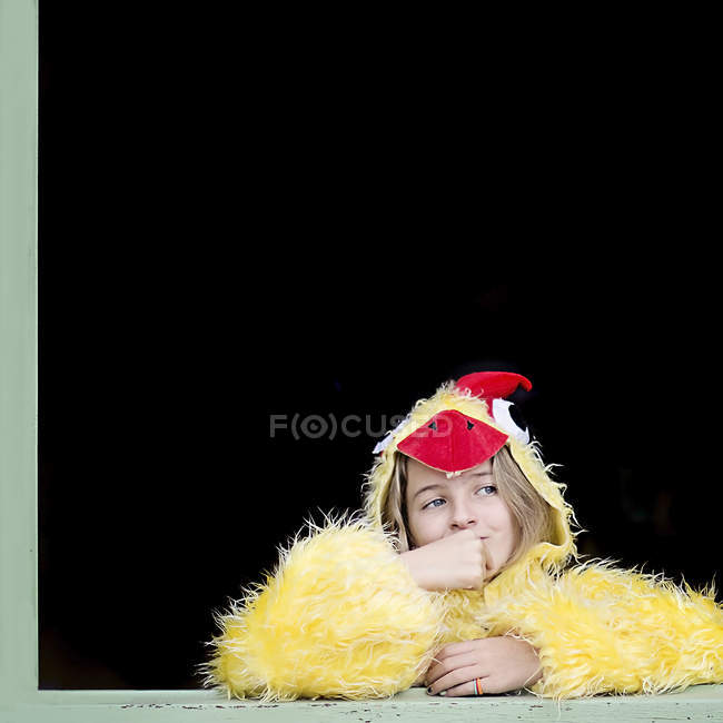 Bambina in finestra vestita con costume giallo pollastrella su sfondo nero — Foto stock