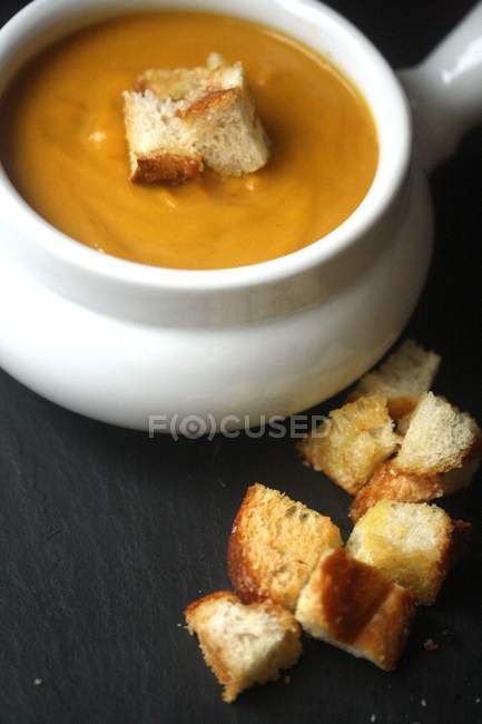 Creamy Pumpkin Soup with croutons over wooden background — Stock Photo