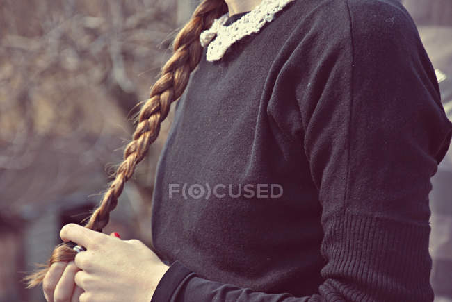 Imagen recortada de colegiala sosteniendo el pelo en las manos - foto de stock