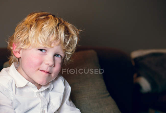 Sorridente ragazzo biondo indossa camicia bianca guardando la fotocamera — Foto stock