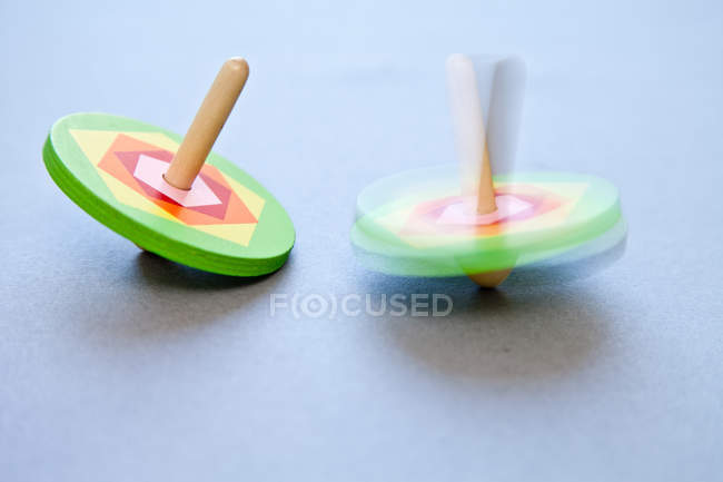 Closeup view of two spinning tops over grey background — Stock Photo