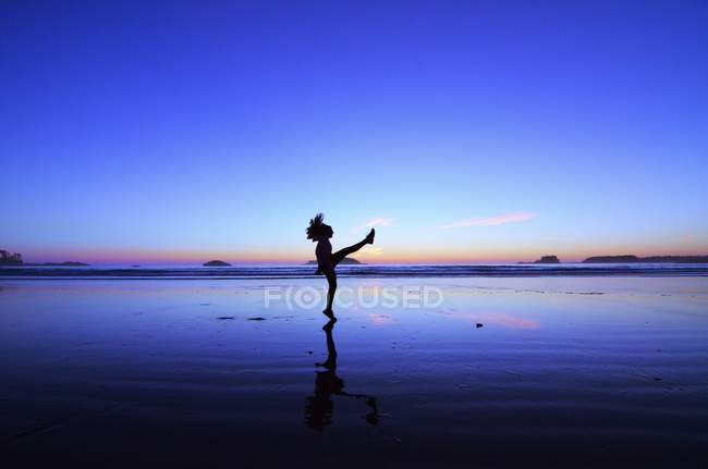 Side view of silhouette of boy kicking on beach — Stock Photo