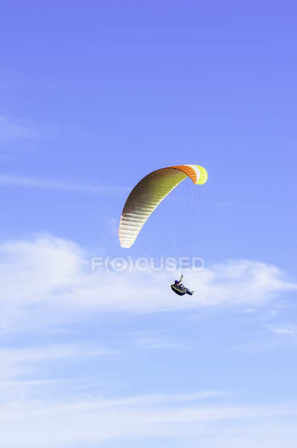 Person paragliding in front of blue sky with clouds — Stock Photo