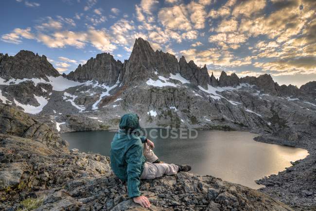 USA, California, Inyo National Forest, Rear view of man sitting on cliff and looking at mountains — Stock Photo